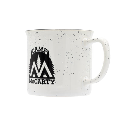 White mug with speckled pattern and 'Camp McCarty' logo on a white background